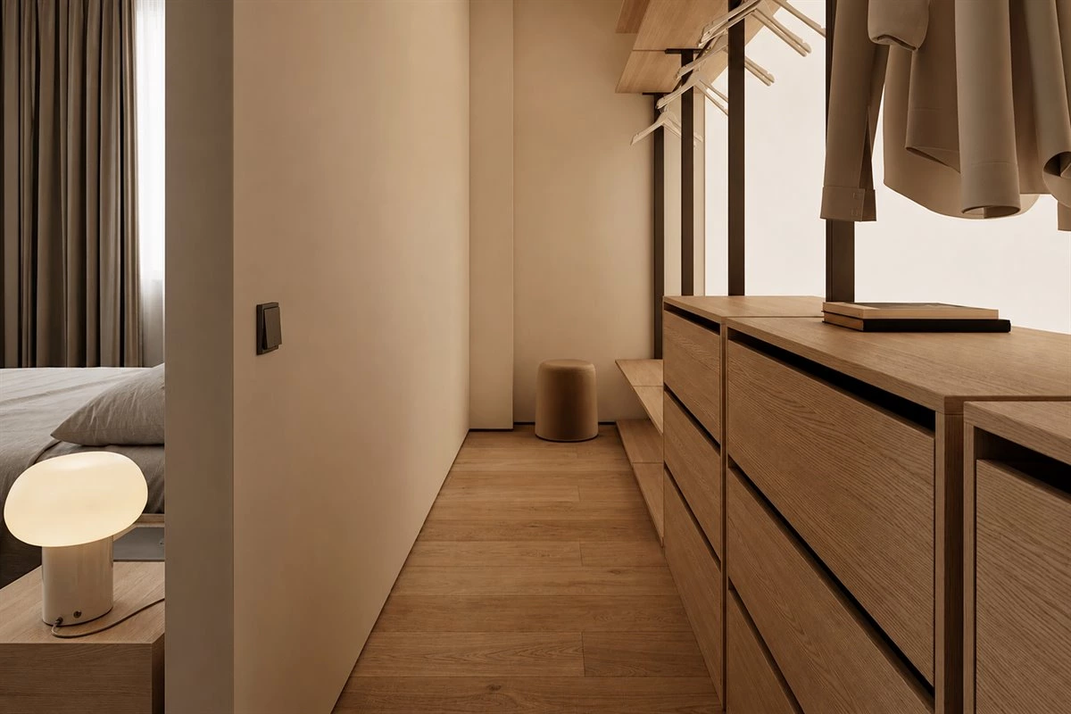 Small galley walk-in closet with oak shelves drawers and warm LED lighting