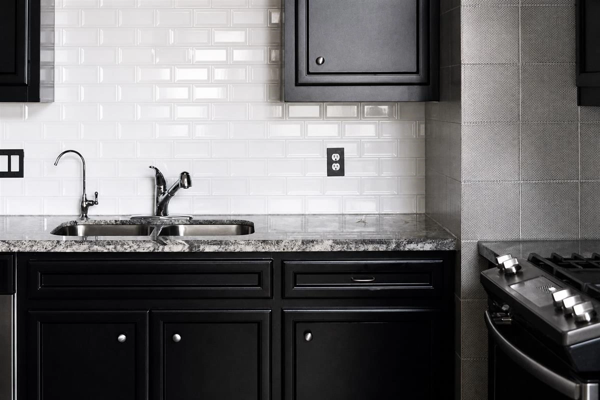 Matte black kitchen cabinets with white backsplash