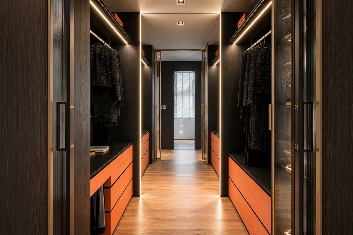Galley walk-in closet with pocket doors glass display cabinets and recessed lighting
