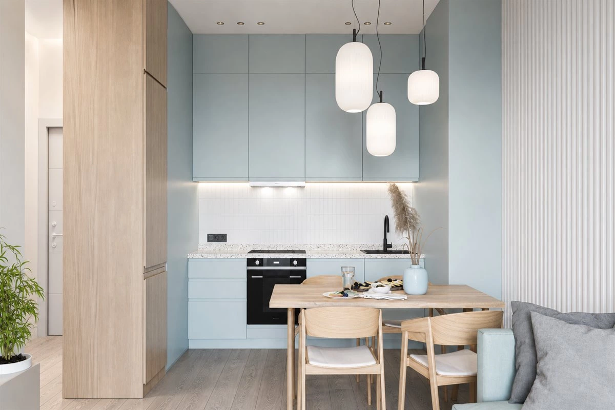 Light blue kitchen cabinets with wood accents white surfaces and natural daylight
