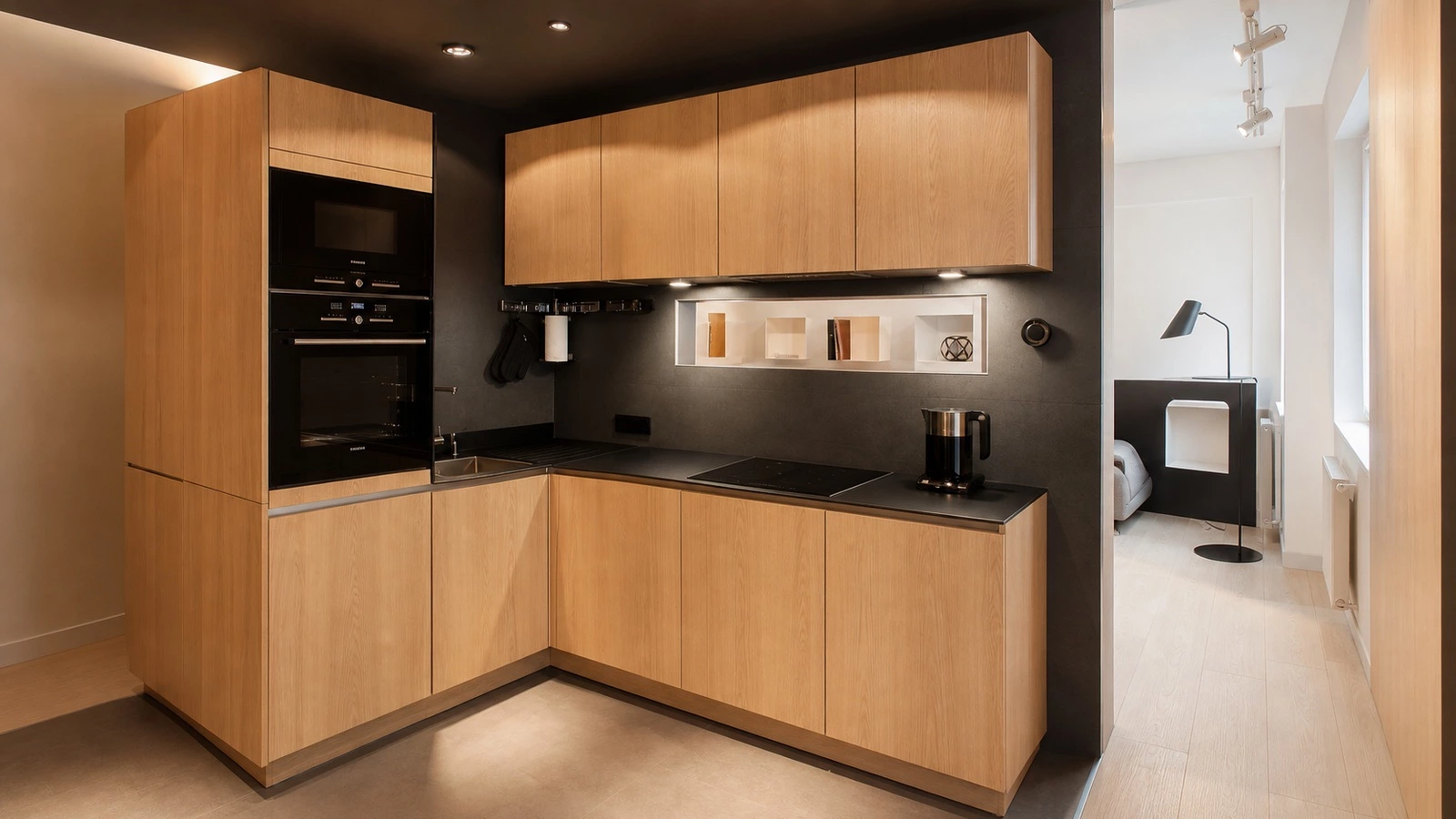 White oak kitchen cabinetry with black backdrop in a small apartment