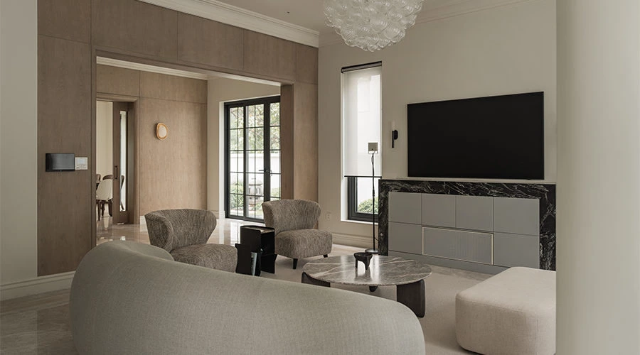 Integrated light grey cabinetry and wood wall panels in a symmetrical living room