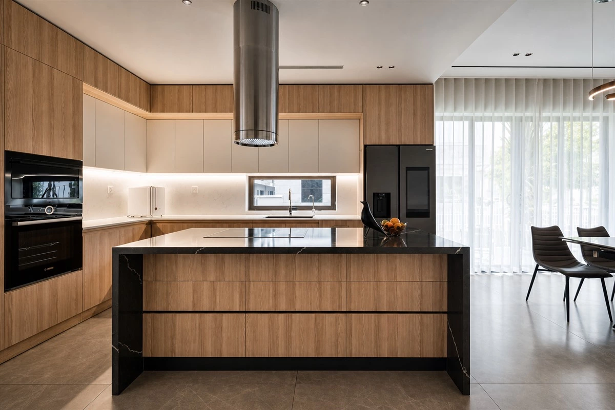 Wood-toned kitchen with oak cabinetry marble countertops and warm lighting