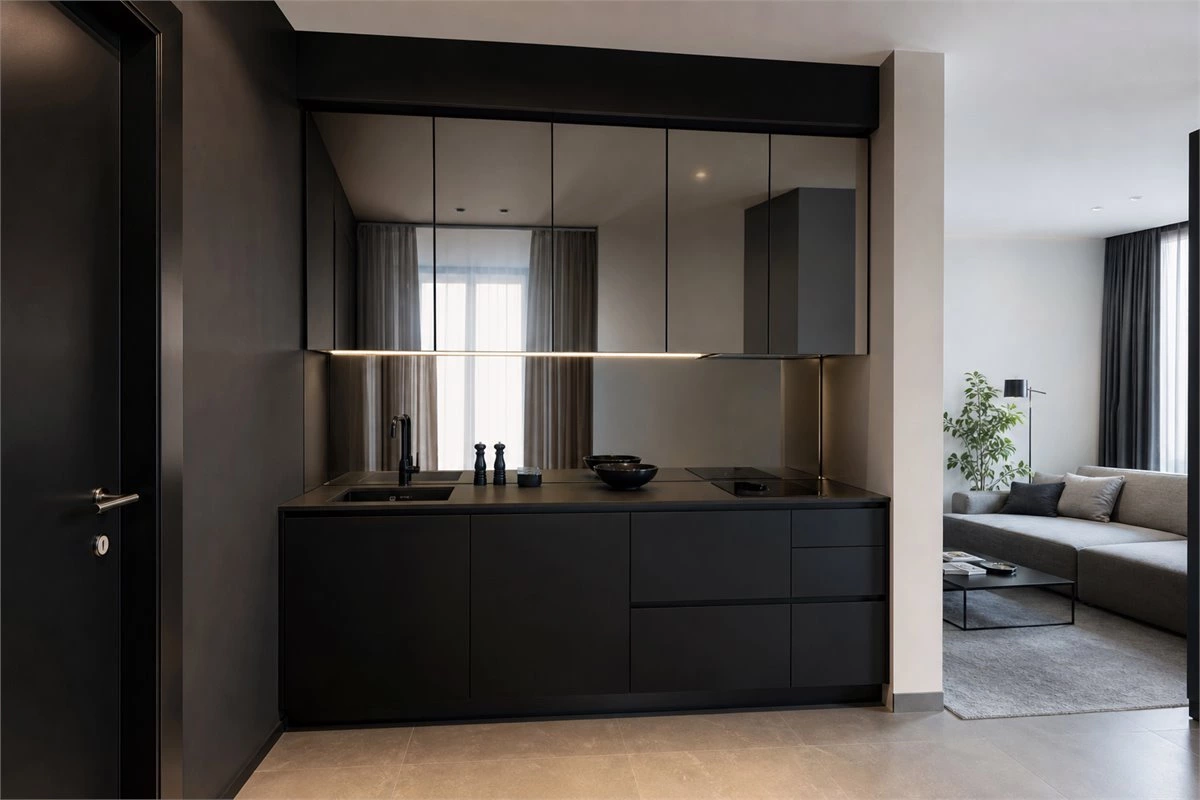 Small black kitchen with reflective backsplash to brighten an open living area