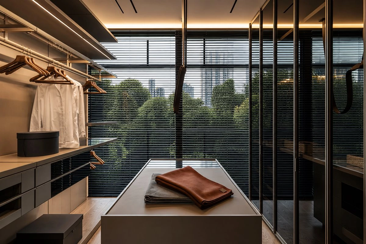 Modern urban walk-in closet with center island open shelving and tinted glass wardrobe