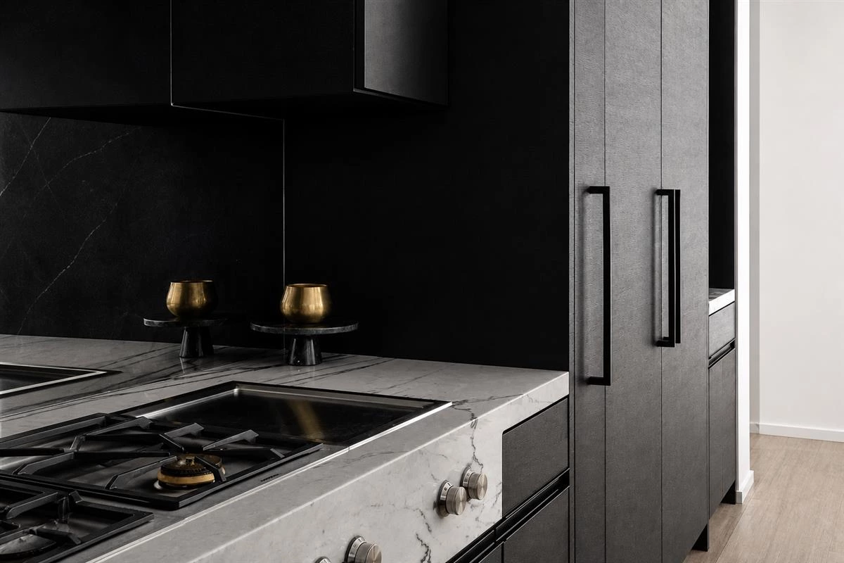 All black kitchen cabinets with light marble countertop