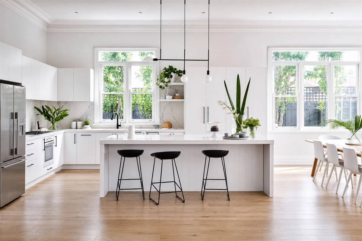 Open airy minimalist kitchen with white cabinets black accents and wood floor