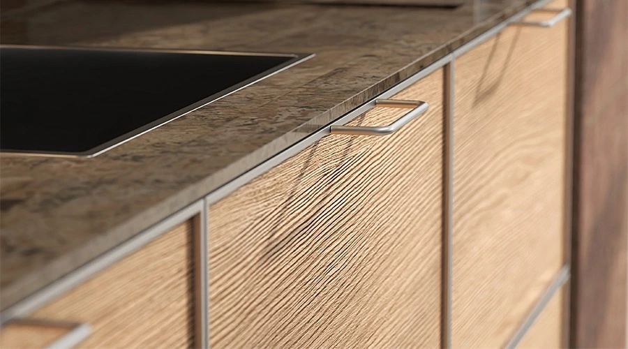 Timber drawer fronts, dark worktop and metal details in an extended island kitchen